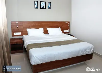 a bedroom with a large bed with a wooden headboard at Hotel Mayo in Wayanad