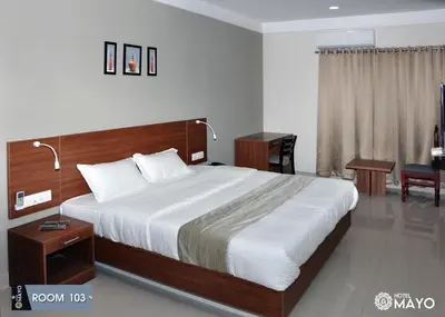 a bedroom with a large bed and a desk at Hotel Mayo in Wayanad