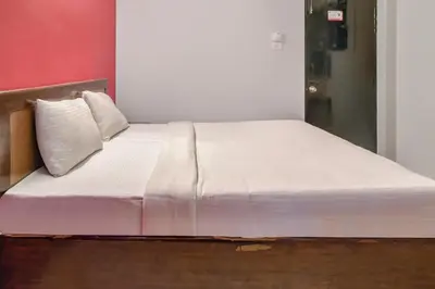 a bed with white sheets and pillows in a room at Hotel O Kota Lodge in Coimbatore