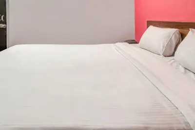 a white bed with white sheets and pillows at Hotel O Kota Lodge in Coimbatore