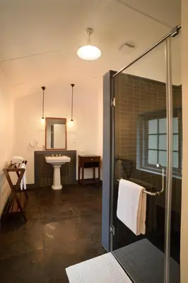 a bathroom with a glass shower and a sink at Ama Stays and Trails Tea Estate Bungalows , Munnar in Munnar
