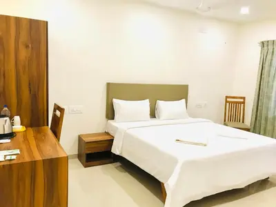 a bedroom with a large white bed and a desk at MALLI resort in Dhārāpuram