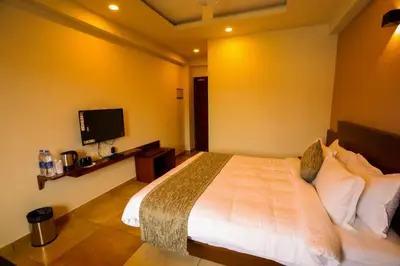 a bedroom with a large bed and a flat screen tv at Zubis Inn Hotel in Kalpetta