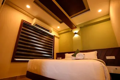 a bedroom with a white bed with a window at Zubis Inn Hotel in Kalpetta