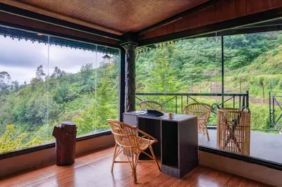 a room with a table and chairs and a large window at The Berg Ooty Queen of Hills in Ooty