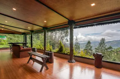 a room with a large window with a table and a bench at The Berg Ooty Queen of Hills in Ooty