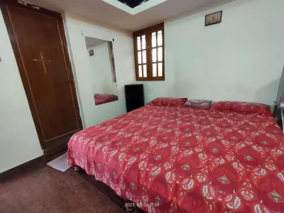 a bedroom with a bed with a red bedspread at Akshay Sweet Home Stay in Mysore