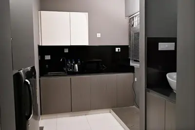 a kitchen with black and white cabinets and a sink at Transit Suites by GrandWest in Nedumbassery