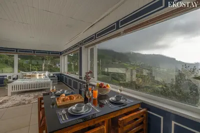 a kitchen with a table with food and a large window at EKO STAY - Woodside Ivy in Ooty