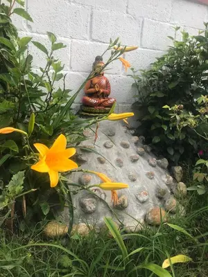 a small statue sitting on a rock in the grass at Kodai Countryside Homestay in Kodaikānāl