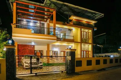 a large yellow house with a balcony at night at Belljem Homes -your own private resort -1 BHK FF in Trichūr
