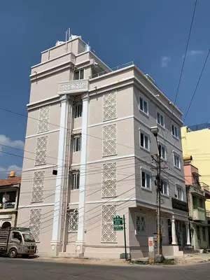 a white building on the corner of a street at Vismaya Comforts in Mysore