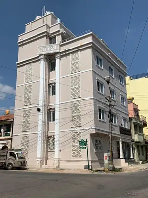 a white building on the corner of a street at Vismaya Comforts in Mysore