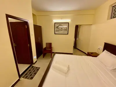a bedroom with a bed and a door and a chair at Aakash Rooms and Cottages, in Ooty