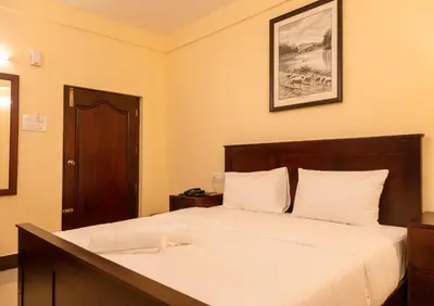 a bedroom with a large bed with white sheets at Aakash Rooms and Cottages, in Ooty