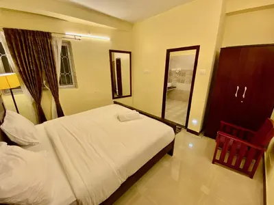 a bedroom with a white bed and a mirror at Aakash Rooms and Cottages, in Ooty