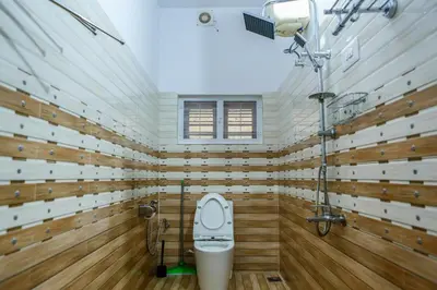 a bathroom with a toilet and wooden walls at Belljem Homes -your own private resort -6 BHK S in Trichūr