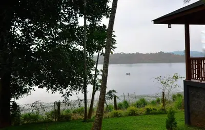 a view of a lake with a boat in the water at LakeRose Wayanad Resort - Water Front Grandeur in Kalpetta