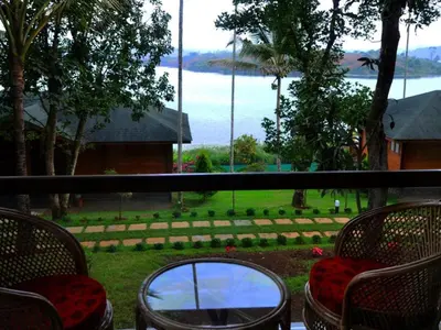 a balcony with chairs and a view of the water at LakeRose Wayanad Resort - Superior lake view in Kalpetta