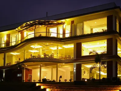 a large building with many windows at night at LakeRose Wayanad Resort - Superior lake view in Kalpetta