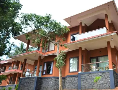 an orange building with a tree in front of it at LakeRose Wayanad Resort - Lake view in Kalpetta