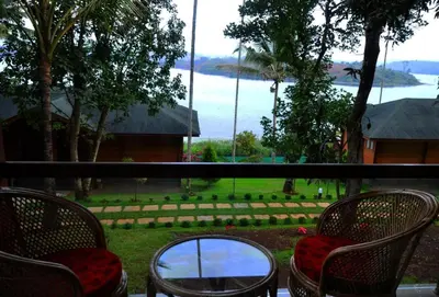 a balcony with chairs and a view of the water at LakeRose Wayanad Resort - Lake view in Kalpetta