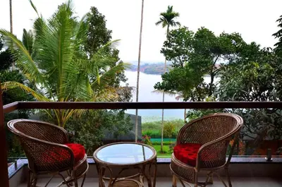 a balcony with two chairs and a glass table at LakeRose Wayanad Resort - Lake view in Kalpetta