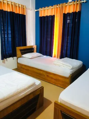 two beds in a room with blue walls and curtains at Royal residency in Tindummal