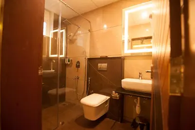 a bathroom with a toilet and a sink and a shower at MC Suites Mysuru in Mysore