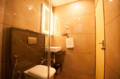 a bathroom with a toilet and a sink and a shower at MC Suites Mysuru in Mysore