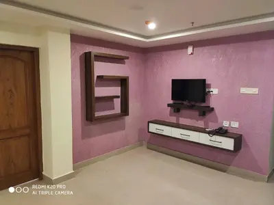 a living room with a tv on a purple wall at Hotel Sree Gokulam Apartments in Guruvāyūr