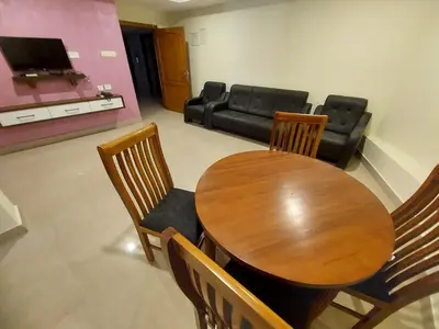 a dining room with a table and chairs and a couch at Hotel Sree Gokulam Apartments in Guruvāyūr