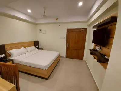 a bedroom with a bed and a wooden door at Hotel Sree Gokulam Apartments in Guruvāyūr