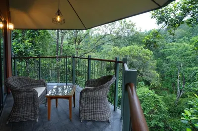a porch with two chairs and a table on a balcony at Vyna Hillock Resort in Vythiri