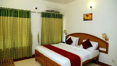 a bedroom with a large bed with green curtains at KTDC Tamarind, Mannarkkad in Alanallūr