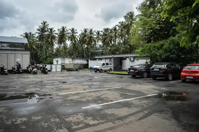 a parking lot with parked cars and palm trees at Nexstay Asma Tower in Kozhikode