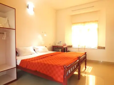 a bedroom with a bed with an orange blanket at Cherai Beach Residency in Cherai Beach