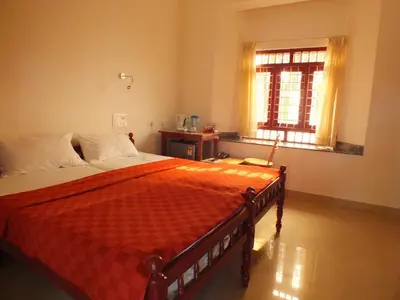 a bedroom with a bed with an orange comforter and a window at Cherai Beach Residency in Cherai Beach
