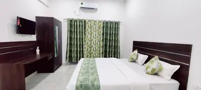 a bedroom with a bed and a desk and a television at Suvarna Elite - Premium Apartment Hotel in Mysore