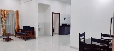 a living room with a chair and a table at Suvarna Elite - Premium Apartment Hotel in Mysore