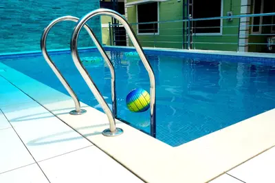 a ball in a swimming pool next to two metal bars at NARMADA POOl VILLA in Angādipuram
