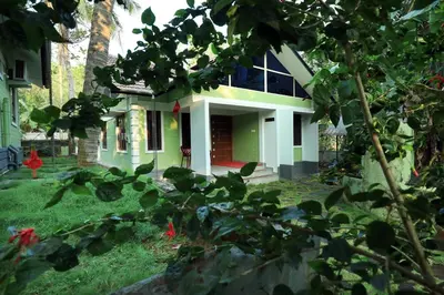 a green and white house with a tree at NARMADA POOl VILLA in Angādipuram