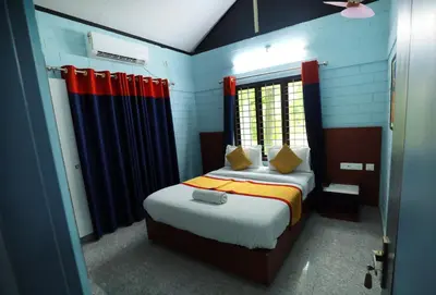 a bedroom with a bed with red and blue curtains at NARMADA POOl VILLA in Angādipuram