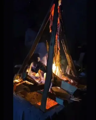 a stove with a fire in it at night at Bohemian Hideaway by Futurve in Kodaikānāl