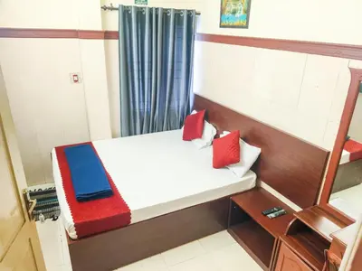a small room with a bed with red and blue pillows at New AS Tourist Home Aluva in Cochin