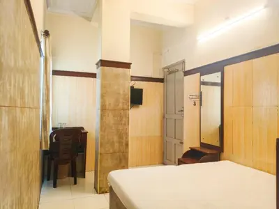 a bedroom with a bed and a table and a chair at New AS Tourist Home Aluva in Cochin