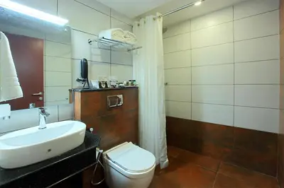 a bathroom with a white sink and a toilet at Lumbini Supreme in Trichūr