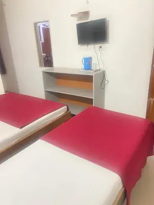 a small room with two beds and a tv at Star Residency in Mysore