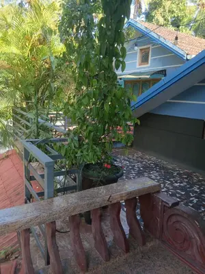a wooden bench in front of a house with a tree at Ben's Villa Kannur ! in Kannur