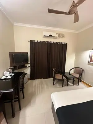 a room with a bed and a desk and a television at GD International Redfort in Nilambūr